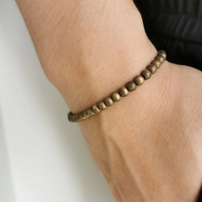 Wrist wear shot of copper brass beads bracelet fitted on human wrist, demonstrating slim comfortable fit