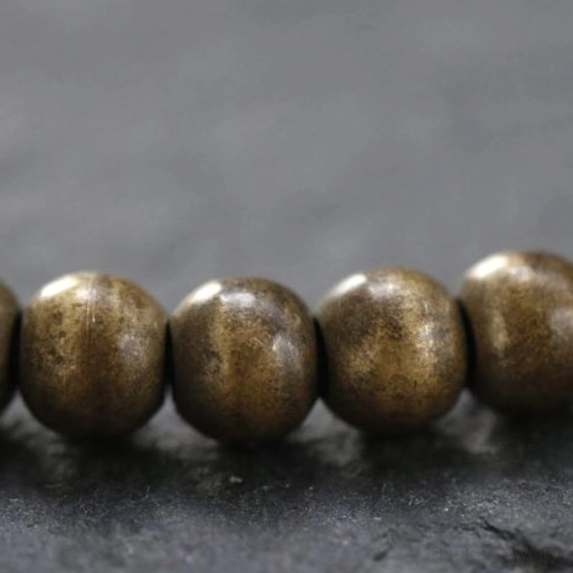 Extreme macro close-up of matte copper brass beads showing surface texture and round bead detail