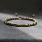 Copper brass beads bracelet with adjustable pull cord closure, round matte beads photographed on dark slate surface