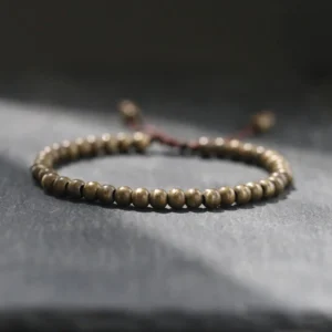 Copper brass beads bracelet with adjustable pull cord closure, round matte beads photographed on dark slate surface