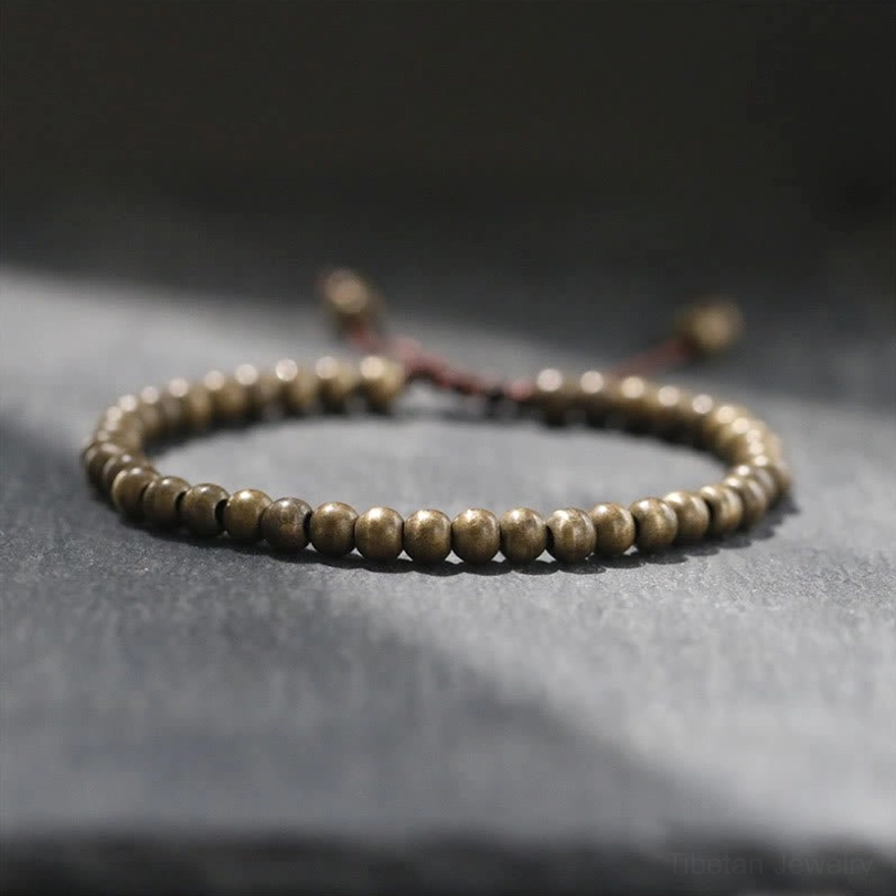Copper brass beads bracelet with adjustable pull cord closure, round matte beads photographed on dark slate surface