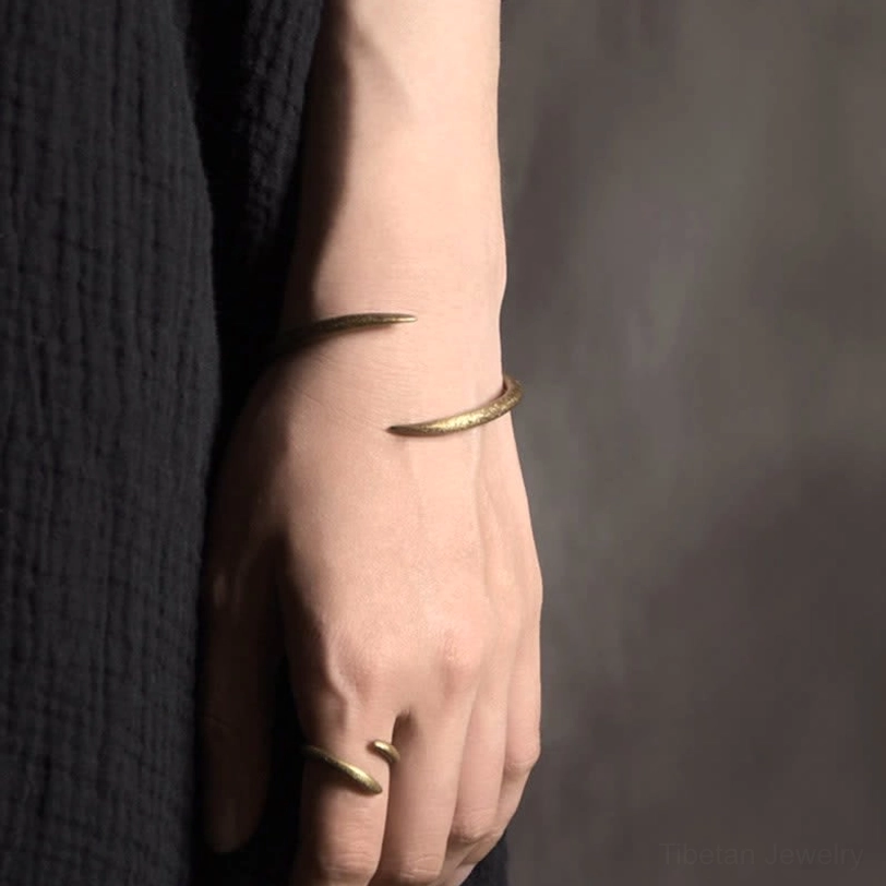 Copper claw cuff bracelet paired with matching copper ring, aged gold tone, worn on hand and wrist, black linen background