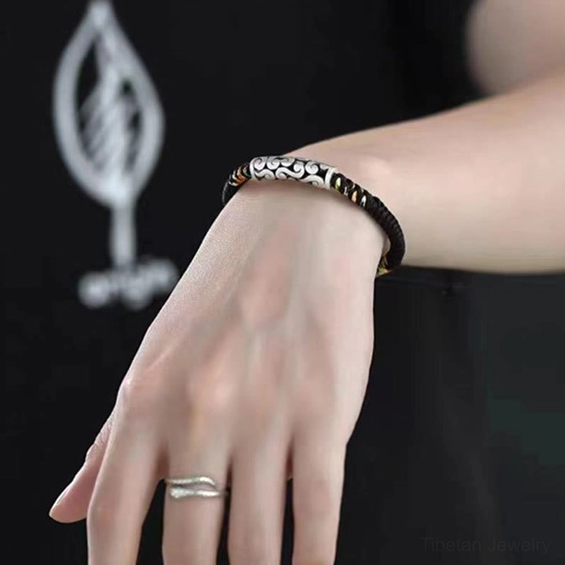Tibetan copper auspicious cloud bracelet closeup on wrist showing silver cloud charm and detailed cord craftsmanship