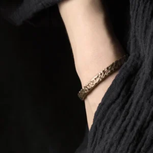 Copper adjustable cuff bracelet worn on ankle, side view close-up showing hammered bronze metal band with black linen