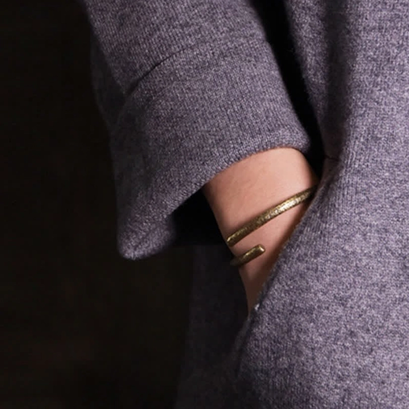 Layered copper cuff bracelets worn on wrist, dual thin and thick design with grey wool coat