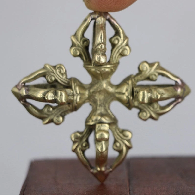 Authentic handcrafted copper double dorje vajra held in hand, top-down close-up view showing intricate 5-prong cross design with carved scroll details