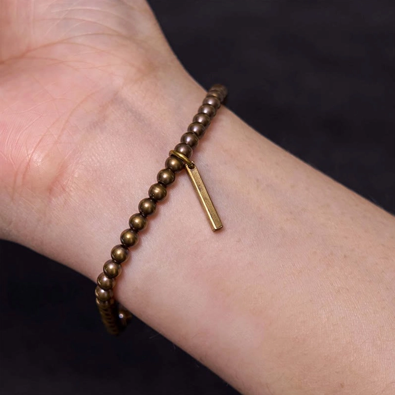 Inner wrist close-up of elastic copper bracelet showing metallic dark bronze color