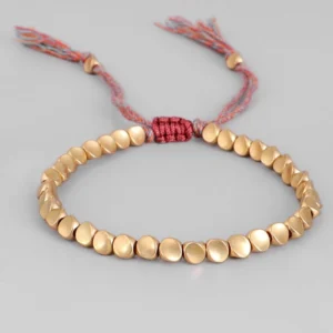 Adjustable copper beads bracelet featuring matte gold round beads with red woven fixing knot and pink-red tassel