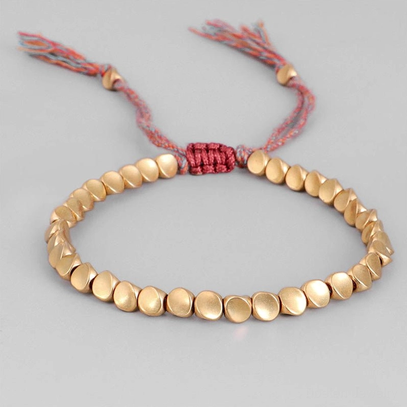 Adjustable copper beads bracelet featuring matte gold round beads with red woven fixing knot and pink-red tassel