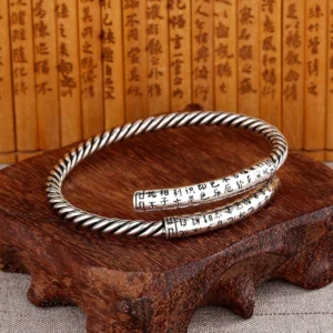 Copper Heart Sutra twisted bracelet pair - top-down flat lay view showing engraved sutra text and twisted rope pattern on wooden display stand