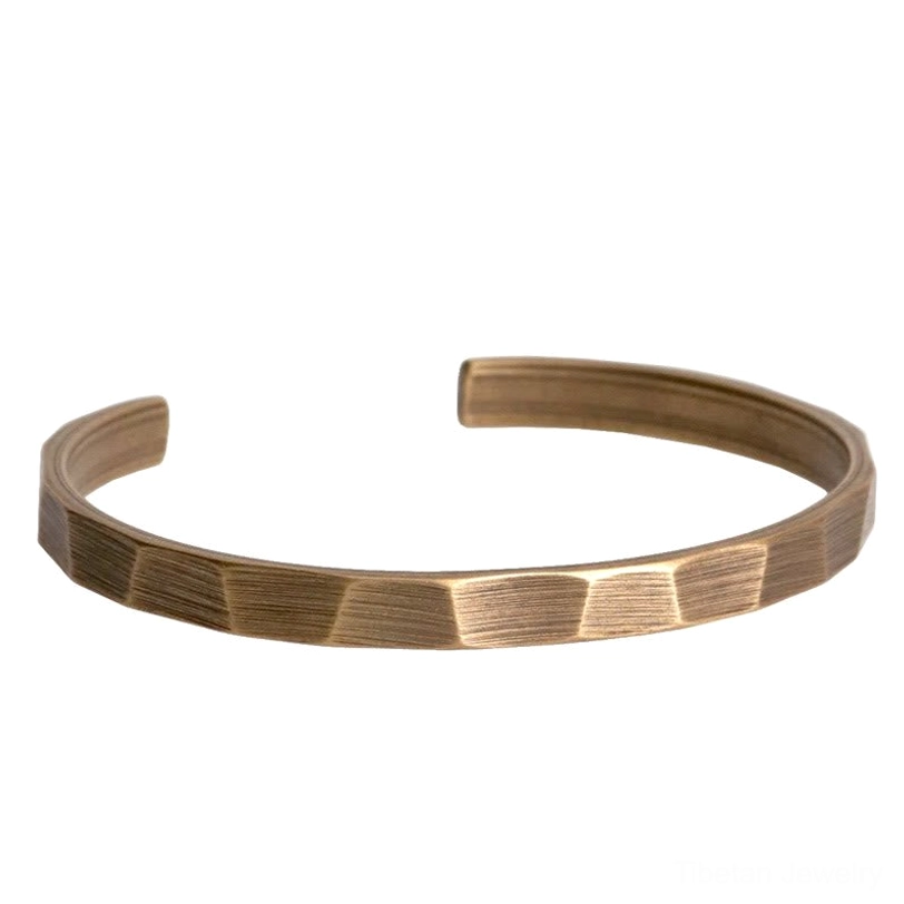 Copper wealth cuff bracelet worn on wrist dark denim faceted textured band ankle wear option