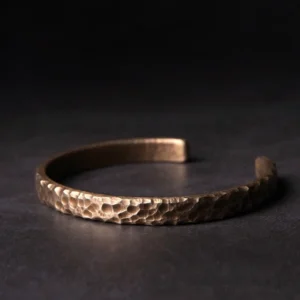 Top-down flat lay of hammered copper adjustable cuff bracelet with bronze tone textured finish