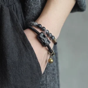 Couple bracelets worn on wrists together showing double strand design and metal bell pendant