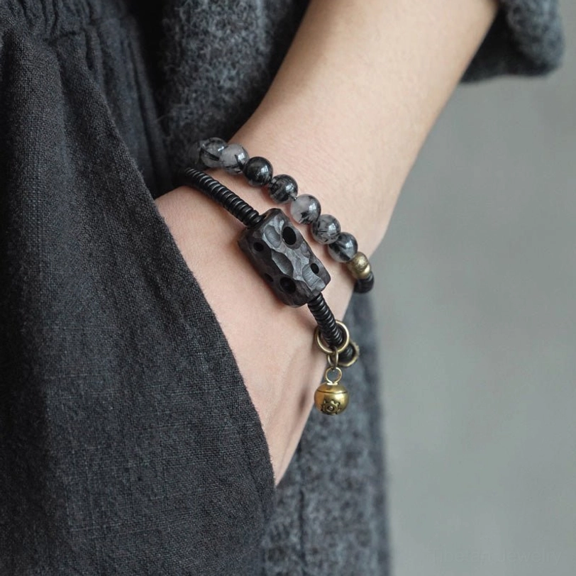Couple bracelets worn on wrists together showing double strand design and metal bell pendant