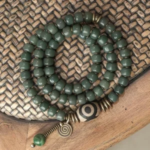 Cyan bodhi seed three-eye dzi triple wrap bracelet with bronze hardware - top down view on wooden surface