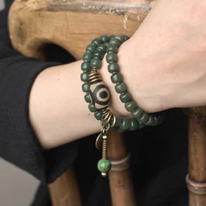 Cyan triple wrap bodhi and dzi bead bracelet worn on wrist - close-up lifestyle shot