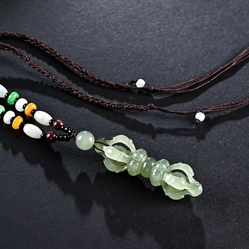 Cyan Hetian Jade Dorje Vajra necklace with black braided cord and multicolor spacer beads, overhead three-quarter view on dark surface
