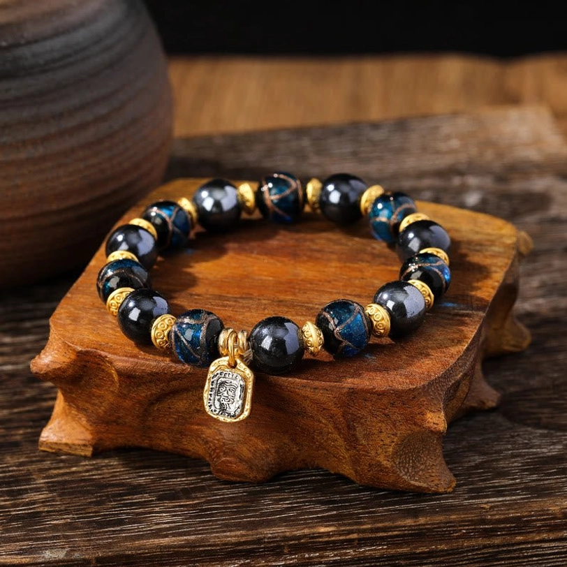 Dark blue-black liuli glass wealth bracelet close-up side view with glossy beads and engraved square charm