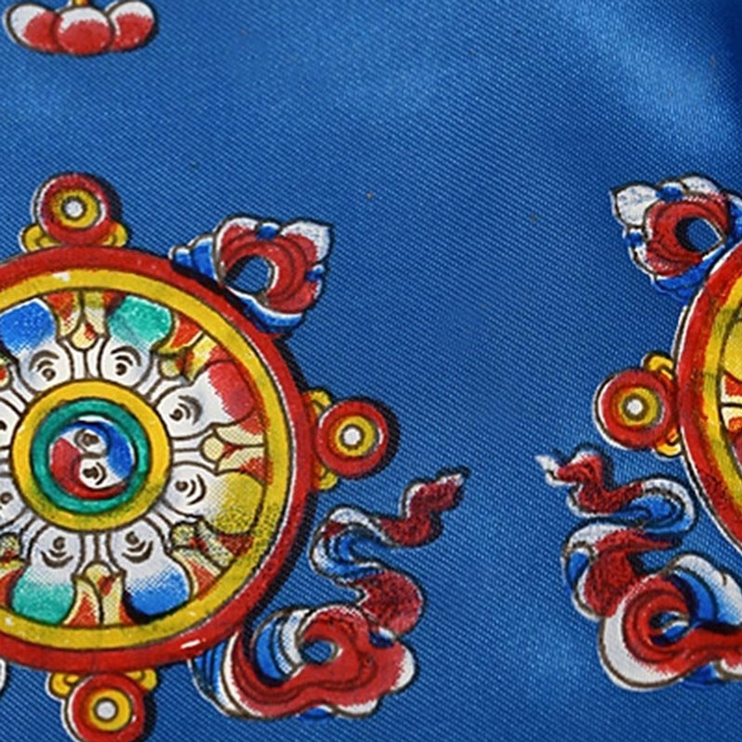 Macro photograph of dharma wheel pattern printed on Tibetan khata scarf with colorful Buddhist symbols and decorative border