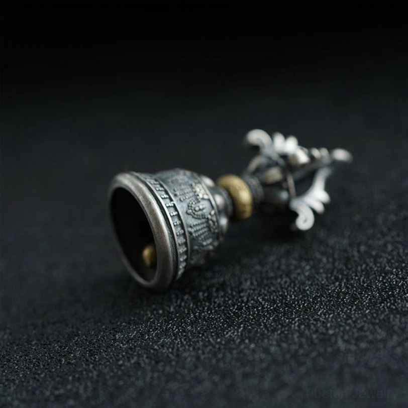 Inverted dorje bell pendant displaying engraved Om Mani Padme Hum Sanskrit mantras and detailed brass accents