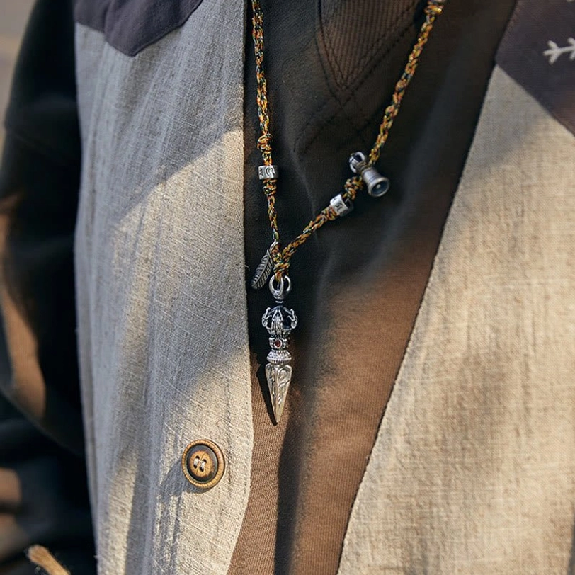 Side view of Dorje pendant necklace with silver bell charm and ritual pendant details, worn with casual jacket