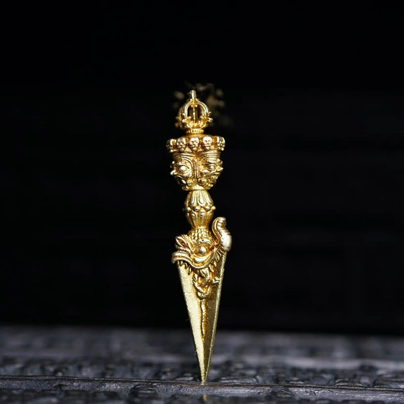 Dorje Vajra ornament frontal view on carved dark base, gold-toned finish with multi-dimensional deity carving details and spiritual engravings