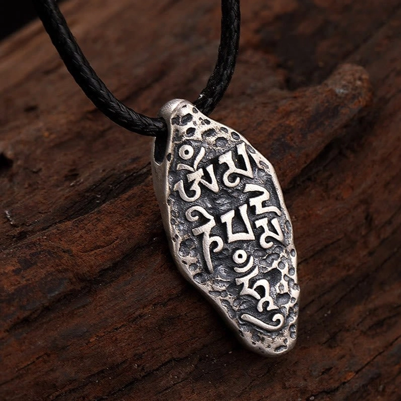 Tibetan Dorje pendant with black wax cord attachment, showing clear mantra engravings and vintage silver tone