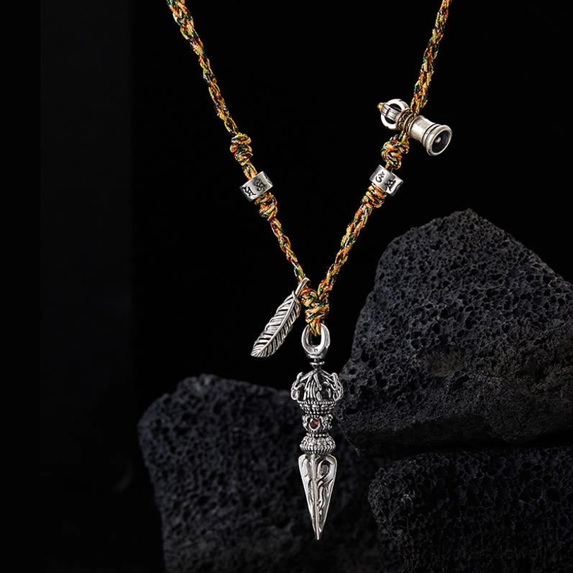 Close-up front view of Om Mani Padme Hum silver Dorje pendant necklace with engraved beads and feather charm on dark background