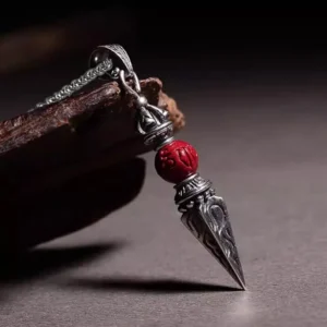 Dorje vajra pendant side angle showing antique silver metalwork details and carved cinnabar stone