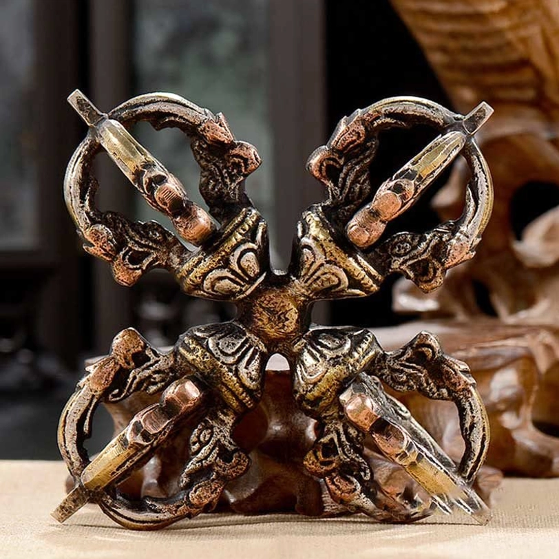 Front overhead view of handcrafted dorje vajra displayed on carved wooden stand with four-way prongs and ornate religious carvings