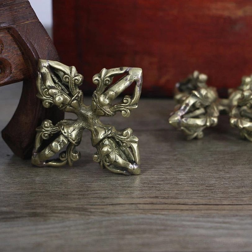 5-prong double dorje vajra from overhead angle, featuring bronze finish compact cross shape with detailed carved prongs on wooden stand