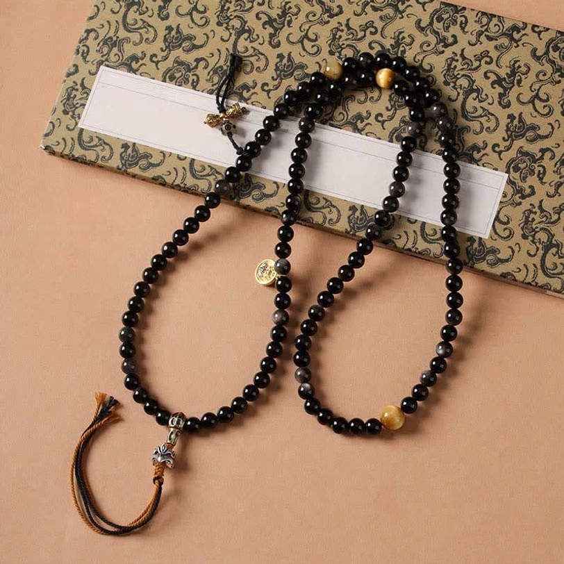 Double-strand Tibetan obsidian prayer necklace with brown tassel and gold accent beads vintage backdrop