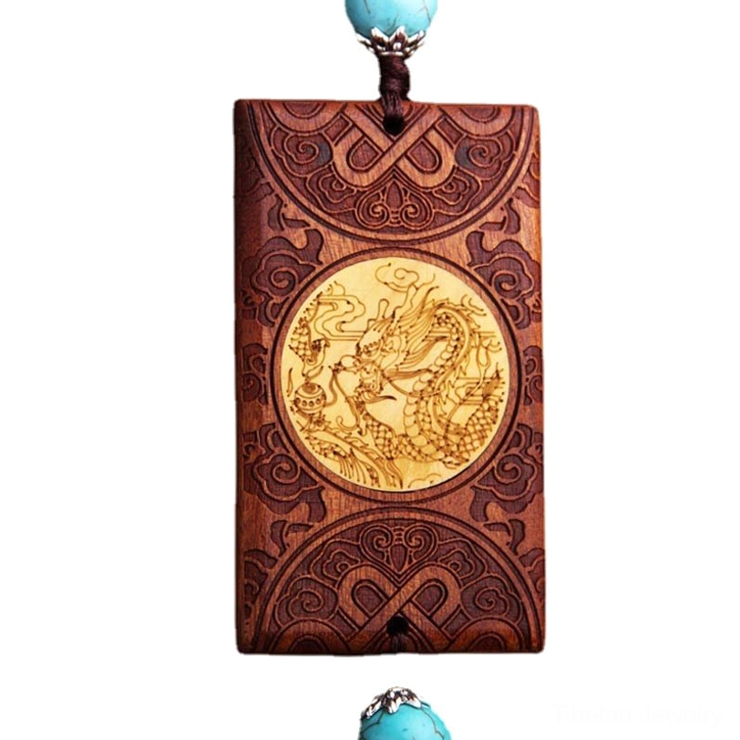 Centered front view of Tibetan dragon car hanging showing dragon medallion, carved borders, and turquoise bead accent