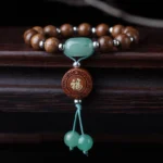 Dragon wood Tibetan blessing bracelet with om mani padme hum beads, green jade accents, and silver spacers displayed on dark wood surface