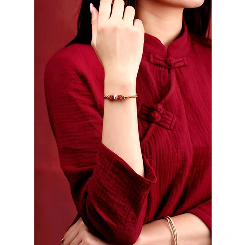 Tibetan protection bracelet on forearm with traditional red clothing background