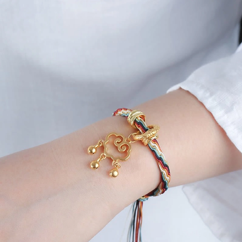 Colorful tibetan healing bracelet worn on wrist with white sleeve, cloud lock bell pendant visible