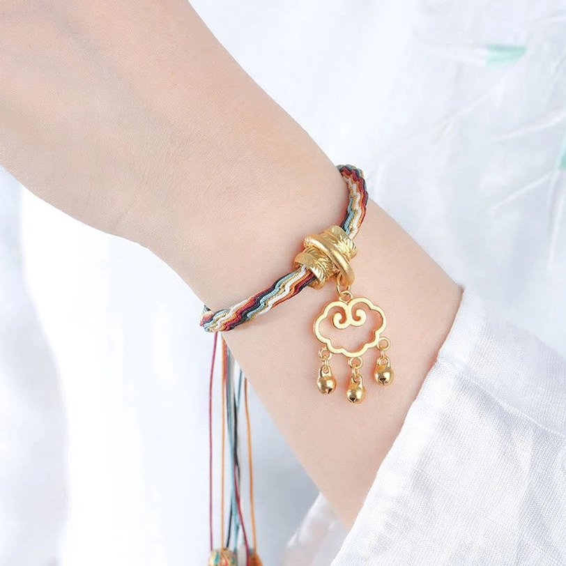 Tibetan lucky bracelet side close-up showing multicolor woven strap, gold clasp, and cloud lock tassel pendant