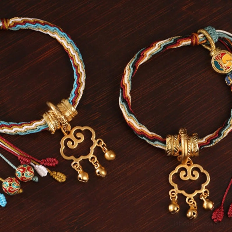 Dunhuang style lucky bracelet with light mixed braided cords, enamel charms, and gold cloud lock pendant on wooden surface