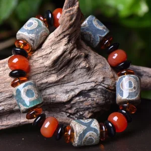 Three-Eye Dzi Bead protection bracelet - side angle view rested on rustic driftwood, displaying vintage stone texture and warm-toned beads detail