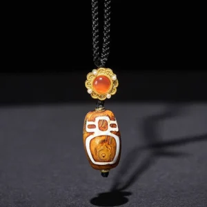 Tibetan brown agate dzi bead with carved nine-eye symbols and gold decorative cap with red stone accent