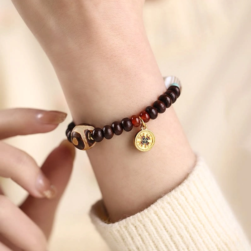 Dzi bead bracelet on wrist lifestyle shot showing striped agate dzi, bodhi beads, enamel charm, and gold spacers worn daily