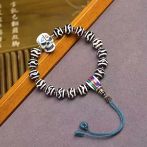Tibetan Dzi Bead protection bracelet angled view showcasing striped beads, colorful spacer, and white skull pendant
