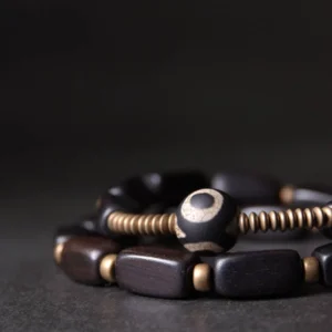 Close-up side view of hand-painted dzi bead with copper coil spacers and dark wood beads detail