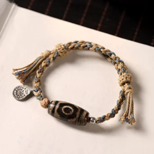 Tibetan dzi bead wealth protection bracelet flat lay white background khaki braided cord