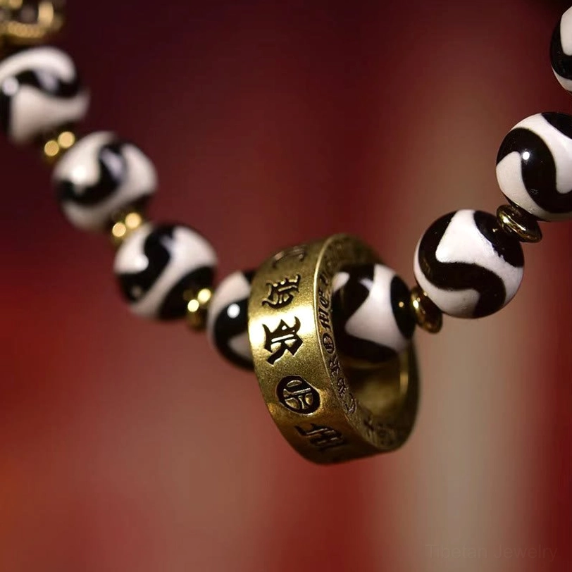 Close-up macro detail of Nine-Eye Dzi Bead bracelet showing hand-painted bead patterns, Tibetan engravings on copper ring, and fine craftsmanship