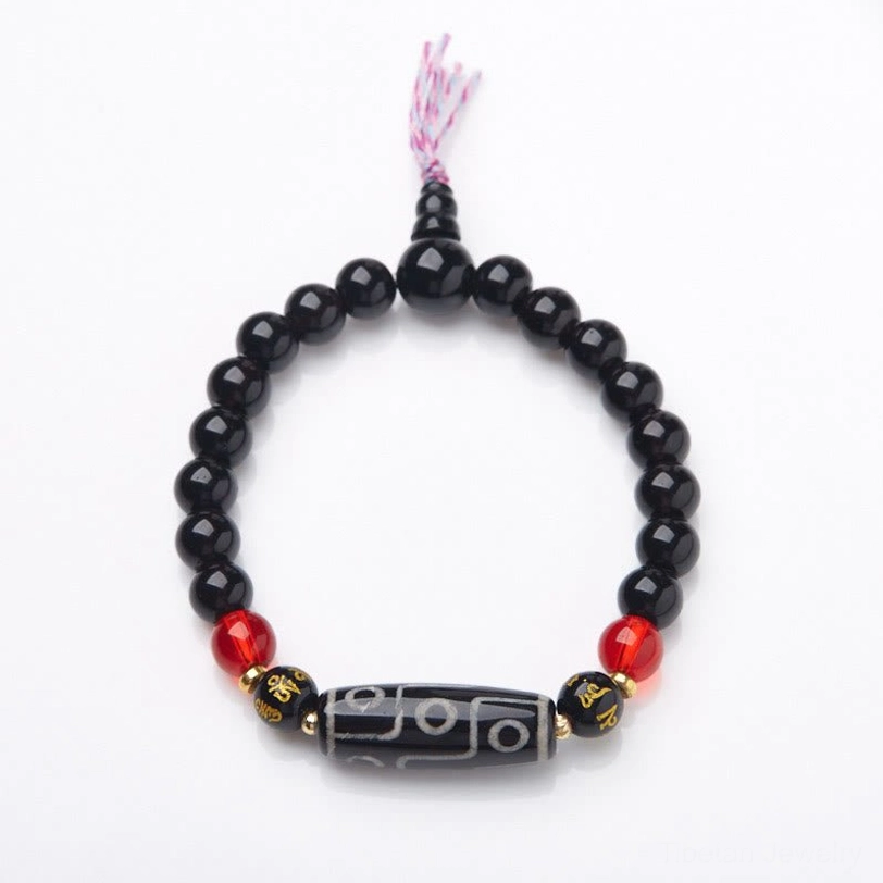 Nine-eye dzi bead bracelet overhead view with pink tassel and gold engraved spacer beads