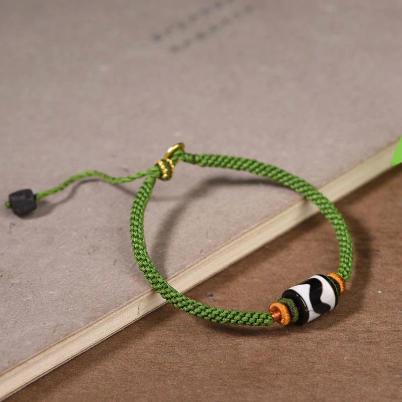 Tibetan dzi bead bracelet angled side view showing green woven rope quality and bead construction