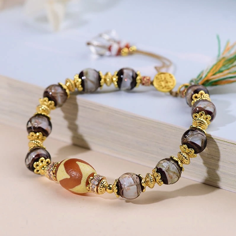 Side angle view of blessing bracelet on wooden book edge showing detailed bead texture and sliding adjuster