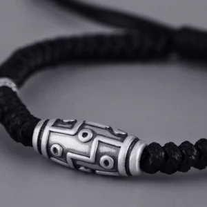 Sterling silver dzi bead bracelet close-up side profile, detailed view of nine-eye engraving and adjustable rope cord