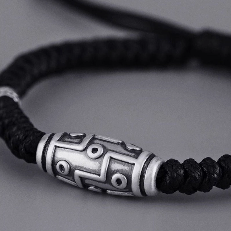 Sterling silver dzi bead bracelet close-up side profile, detailed view of nine-eye engraving and adjustable rope cord